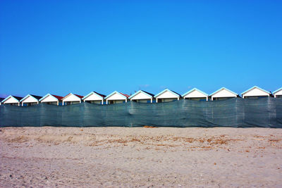 Beach by sea against clear blue sky