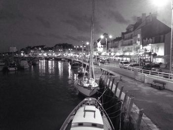 Boats moored at harbor in city at night