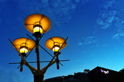 Illuminated street lamp against sky