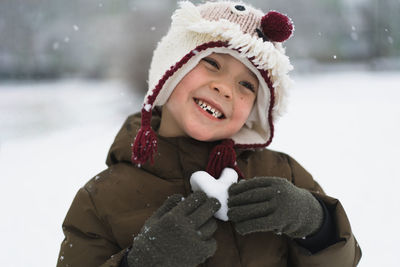 Child enjoying winter. the boy holds a heart made of snow in his hands in winter day. love concept.