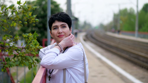 Portrait of smiling woman standing on railroad track