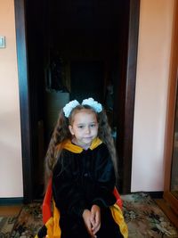 Portrait of girl standing against door at home