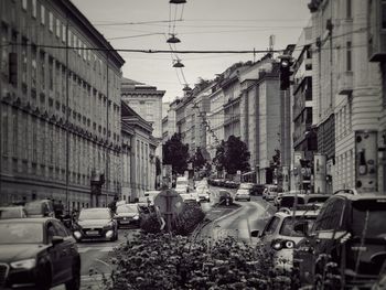 Cars on city street by buildings against sky