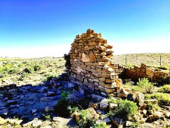 Stack of rocks on field against clear blue sky