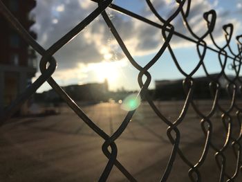 Close-up of chainlink fence against sky during sunset