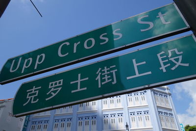 Low angle view of sign board against blue sky