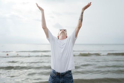 Midsection of woman standing at beach against sky