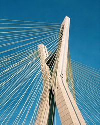 Low angle view of suspension bridge against blue sky