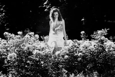 Portrait of confident woman amidst roses at park