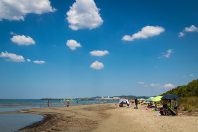 Group of people at beach against sky