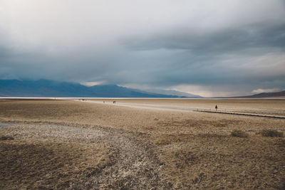 Scenic view of arid landscape against cloudy sky