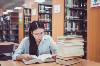 Woman reading book while sitting in library