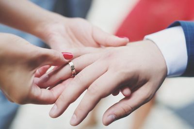 Cropped image of bride putting ring in hand of bridegroom