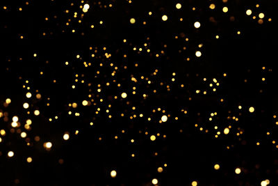 Defocused image of illuminated lights against sky at night