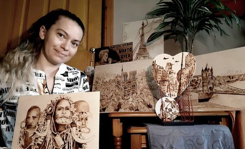 Portrait of smiling young woman sitting on table at home