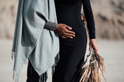 Midsection of couple embracing standing outdoors