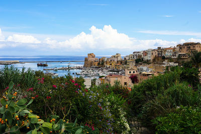 Scenic view of sea by buildings against sky