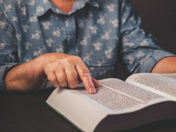 Midsection of man reading book on table