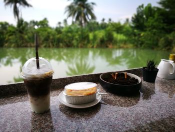 Coffee cup on table against trees