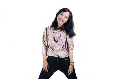Portrait of smiling young woman standing against white background