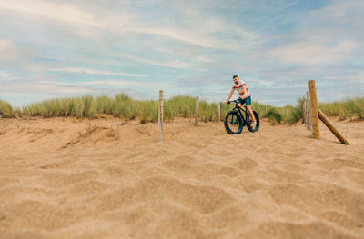 Man riding a fat bike through the beach dunes