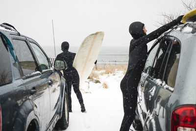 Women getting ready to surf on a snowy day