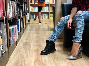 Low section of woman wearing shoe and high heels sitting at library