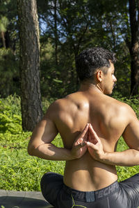 Latin american man doing yoga posture, yoga posture, bee backwards prsthatah brahmara, forest