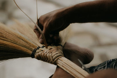 Close-up of person working on handcrafted walis tambo or brooms