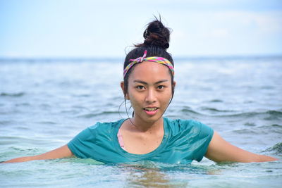 Portrait of young woman swimming in sea against sky