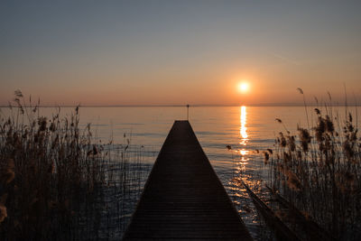 Pier over sea against sky during sunset