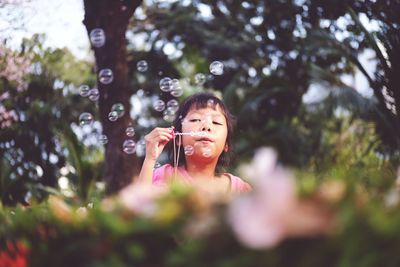 Cute girl blowing bubbles in park
