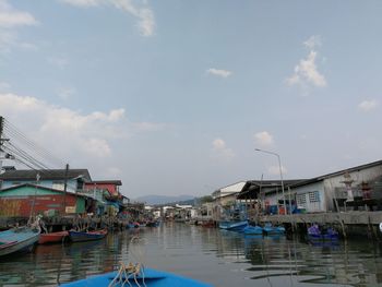 Boats moored at harbor in city against sky