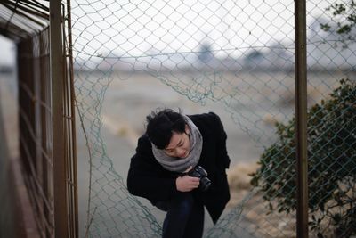 Woman with camera walking in broken fence