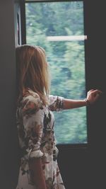 Rear view of woman standing by window