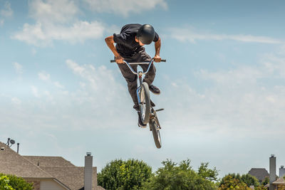 Low angle view of man on bicycle jumping against sky
