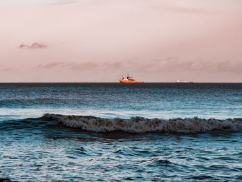 Scenic view of sea and boat against sky during sunset