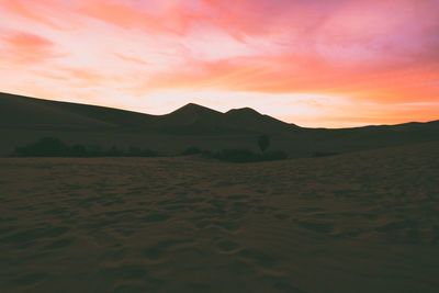 Sand dunes in desert against cloudy sky