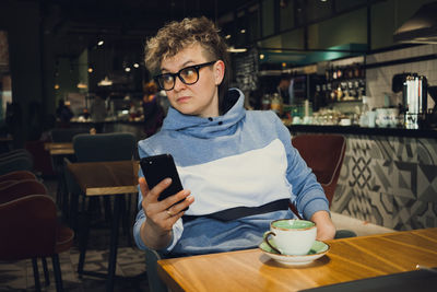 Mature woman using phone sitting at cafe