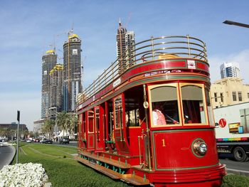 Red tram in city against sky