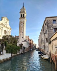 Canal amidst buildings in city against sky