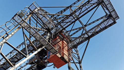 Low angle view of crane against clear blue sky