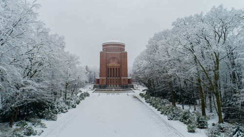 Snow covered road by trees against sky