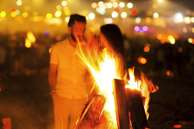 People at illuminated fire at night