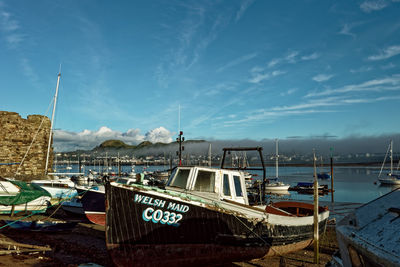 Boats moored at harbor against sky