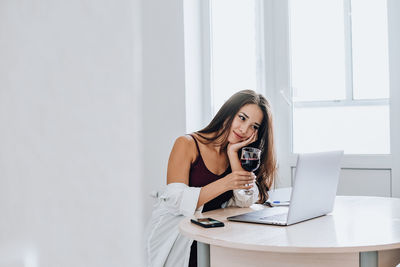 Woman using phone while sitting on table