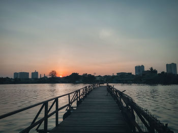 View of river and buildings against sky during sunset