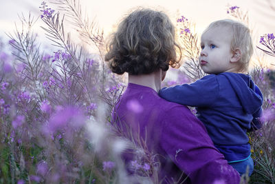 Rear view of people on purple flowering plants