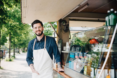 Portrait of young owner standing by commercial land vehicle on street