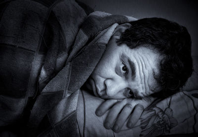 High angle view of thoughtful man lying on bed